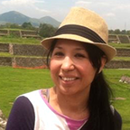 Photo of a smiling woman with tied back, long hair. She is wearing a t-shit and straw hat